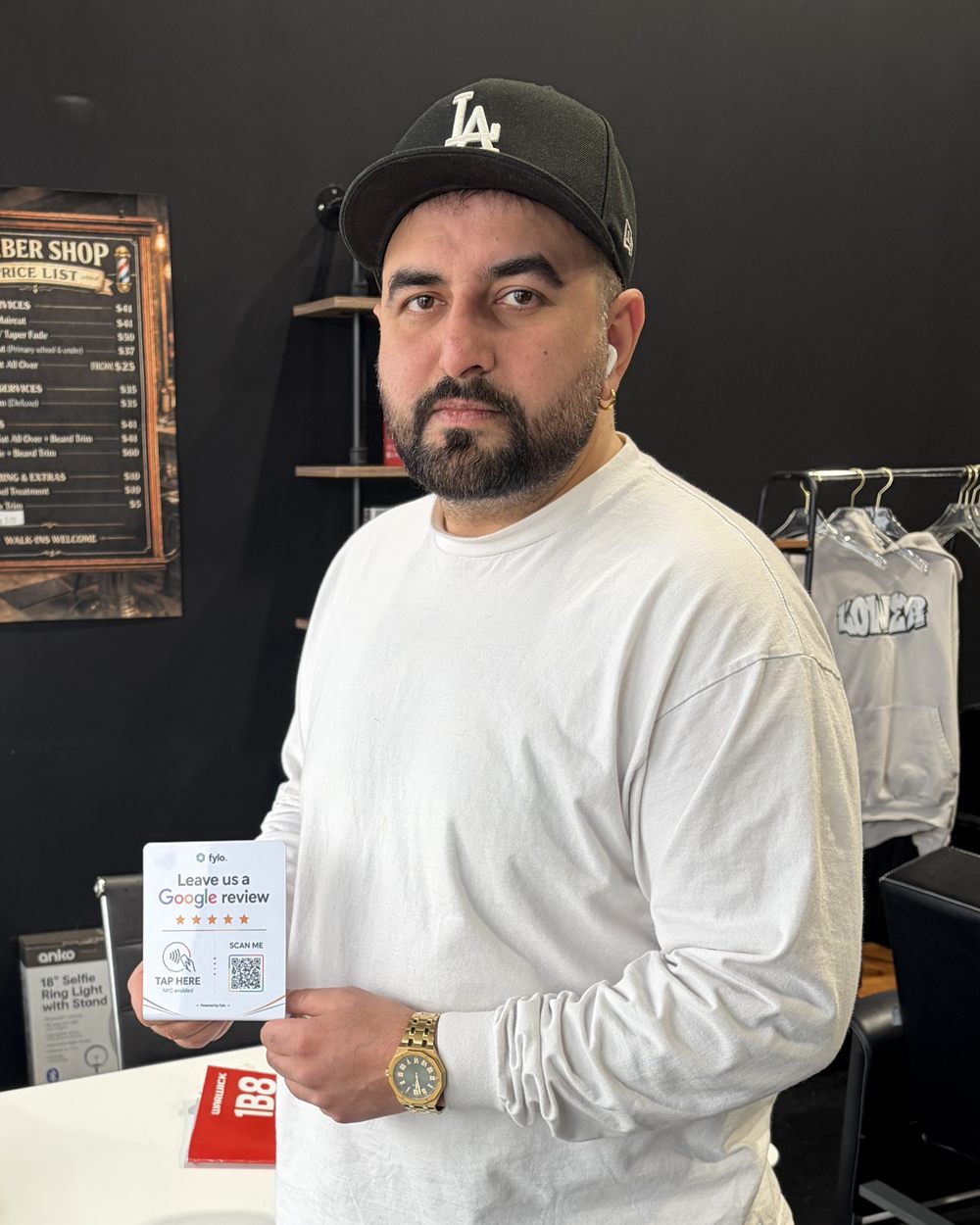 A barber holds a Fylo review stand in front of him in his shop.